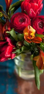 Vibrant red and orange floral bouquet in a vase with a teal background.