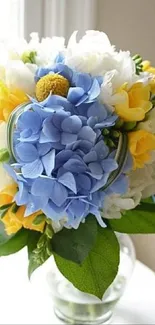 Bright blue, white, and yellow flower bouquet in a glass vase.