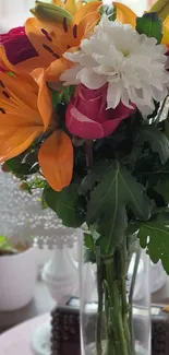 Floral bouquet with colorful lilies and roses in a vase on a table.