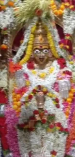 Deity statue adorned with vibrant floral garlands.