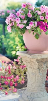 Pink and red flowers in an ornate pot in a garden setting.