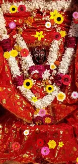 Vibrant goddess idol with red attire and colorful floral adornments.