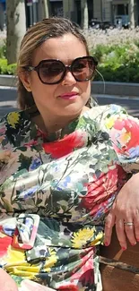 Woman in floral dress sitting on a bench outdoors.