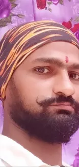 Portrait of a man with a colorful headscarf against a floral background.