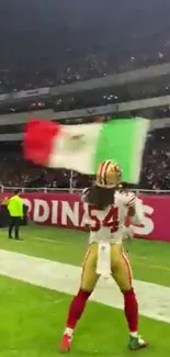 Football player waving flag in celebration at stadium.