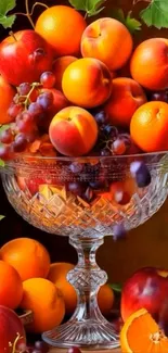 Vibrant assortment of fruits in a glass bowl with leaves.