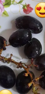 Vibrant wallpaper with grapes and emojis on a floral plate.