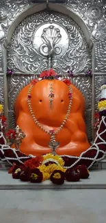 Orange Ganesh idol with ornate details and colorful decor.