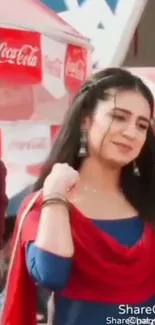 Woman in vibrant red and blue traditional attire smiling at a festival.