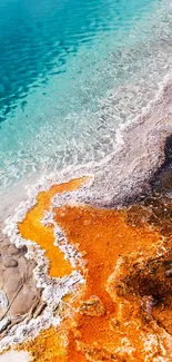 A vibrant geothermal spring with turquoise and burnt orange colors in an aerial view.