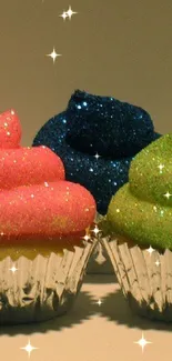 Three glittering cupcakes with pink, blue, and green frosting.