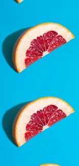 Vibrant grapefruit slices on bright blue background wallpaper.