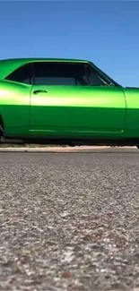 Vibrant green classic car on a road with clear blue sky.