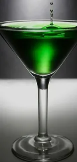 Elegant martini glass with vibrant green cocktail and droplets.