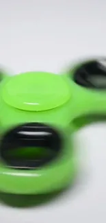 Vibrant green fidget spinner in motion on a white background.