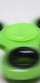 Vibrant green fidget spinner in motion on a minimalist background.