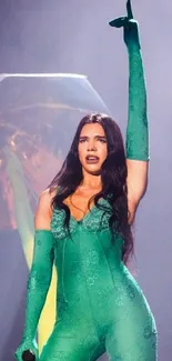 Performer on stage in vibrant green outfit pointing up energetically.