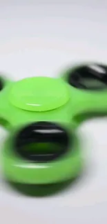 A vibrant green fidget spinner in motion for a dynamic mobile wallpaper.