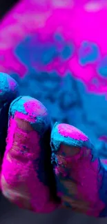 Hand covered in vibrant pink and blue powder, creating a dynamic wallpaper design.