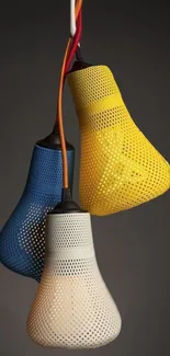 Three colorful hanging lamps in blue, white, and yellow against a dark background.