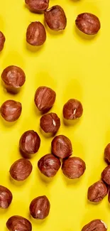 Scattered hazelnuts on vibrant yellow background wallpaper.