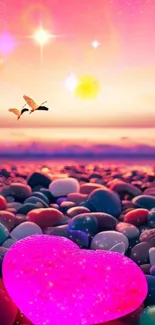 Vibrant pink heart on pebble beach under a colorful sunset sky.