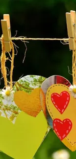 Colorful paper hearts on a string with green background.