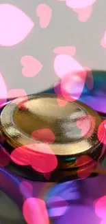 Colorful fidget spinner with pink hearts overlay.