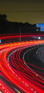 Dynamic red light trails on a highway at night with road signs visible.