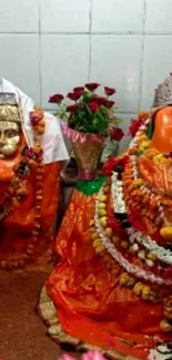 Vibrant Hindu deity decorated with flowers and traditional orange drapery.