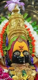 Colorful Hindu deity with gold jewelry and floral garlands.