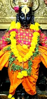 Hindu deity adorned in orange with yellow garlands.