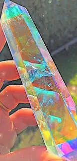 Hand holding a colorful holographic crystal in sunlight.