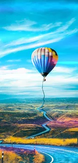 Hot air balloon over scenic road under a vibrant blue sky.