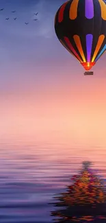 Vibrant hot air balloon reflecting over a serene, purple-hued water at sunset.