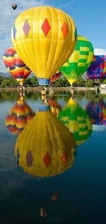 Colorful hot air balloons reflecting on a lake under a blue sky.