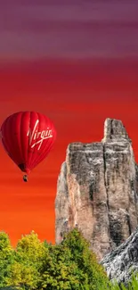 Red hot air balloon with sunset sky, rocks, and greenery.