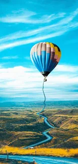 Colorful hot air balloon floating in blue sky over a scenic landscape.