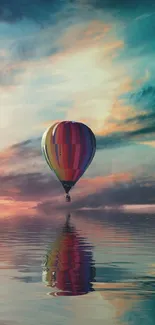 Colorful hot air balloon over reflective water under vibrant sky.