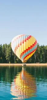 A colorful hot air balloon over a tranquil lake with blue sky.