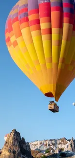 Colorful hot air balloons float over rocky landscape and clear sky.