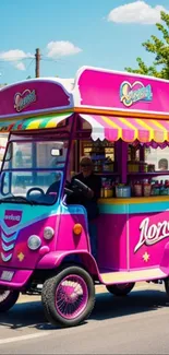 Colorful ice cream cart with vibrant pink and blue design on a sunny street.