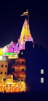 Illuminated temple with colorful lights against a night sky background.