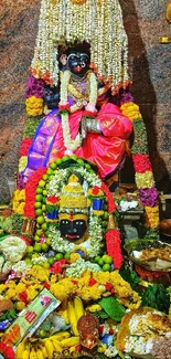 Vibrantly colored Indian deity with flowers and offerings.