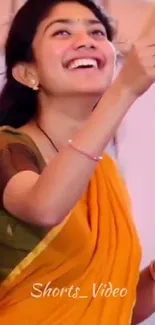 Joyful woman in a vibrant orange sari, smiling happily.