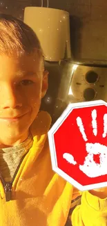 Smiling child in yellow with a handprint stop sign.