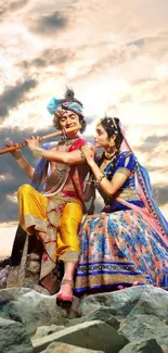 Krishna and Radha in vibrant attire under a mystical cloudy sky on a rocky landscape.