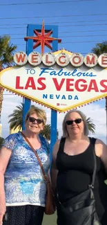 Iconic Las Vegas sign with palm trees and visitors.