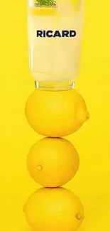 Stack of lemons topped with a glass on vibrant yellow background.