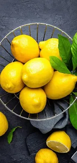 Basket of fresh lemons with green leaves on dark background.